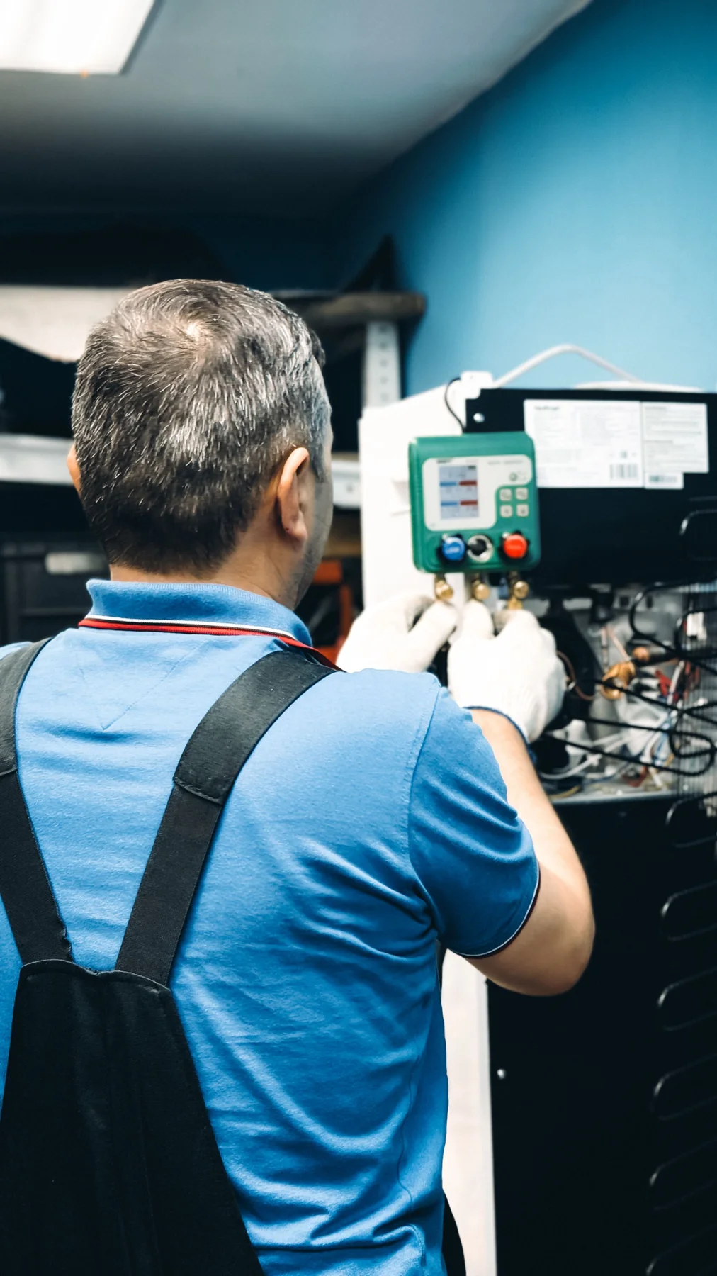 HVAC technician checking air-conditioning equipment with a digital gauge